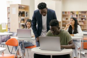 Teacher helping his student with an assignment on his laptop