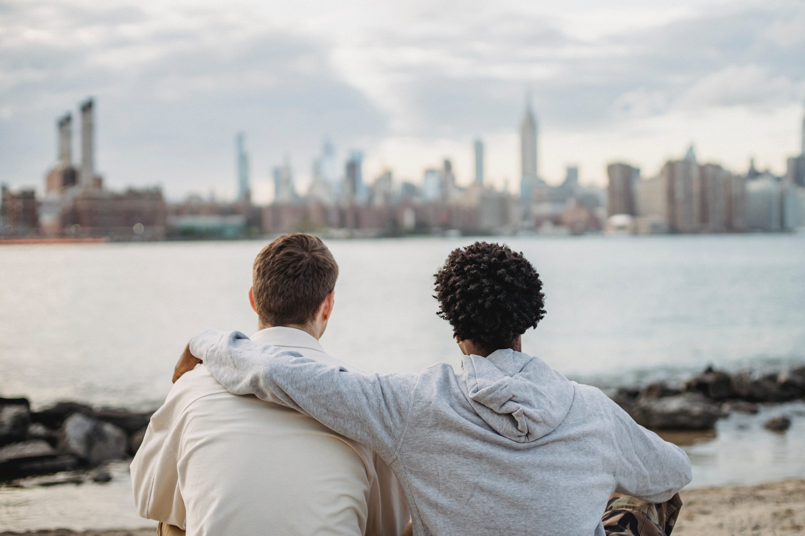 Two friends talking on a beach with their arms around each other