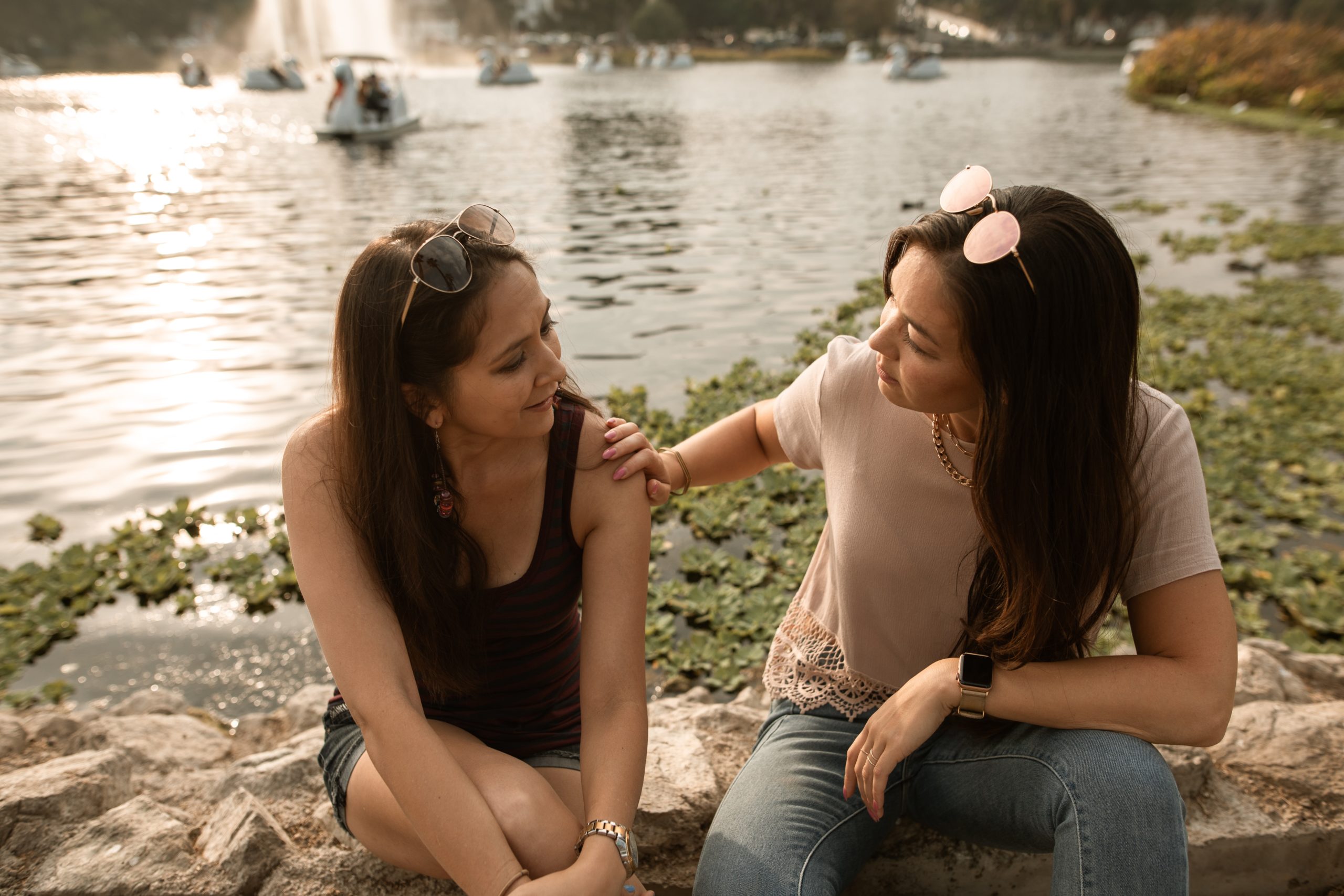Women sitting on rocks near a lake comforting one another