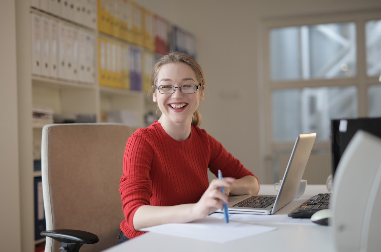 smiling young woman siting at a her desk working on her computer