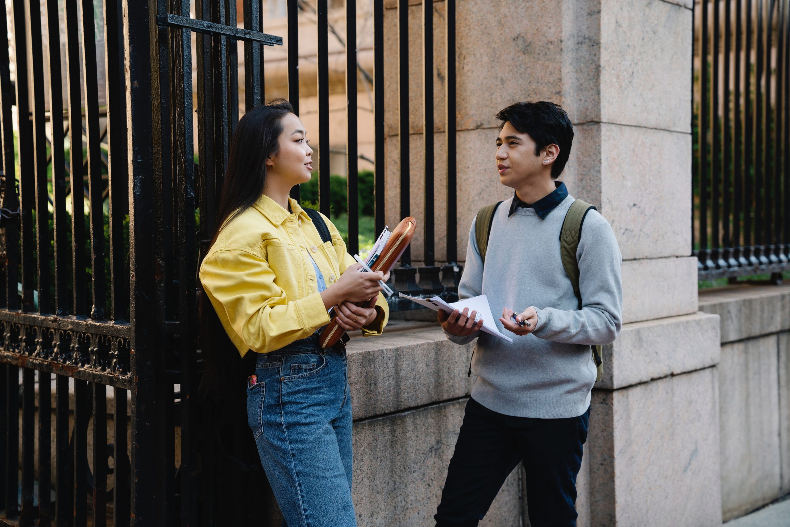 two students talking in front of campus gates