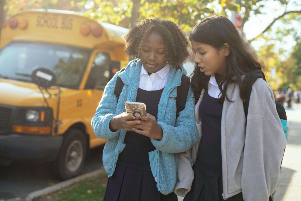 Teen girls looking at phone outside of school
